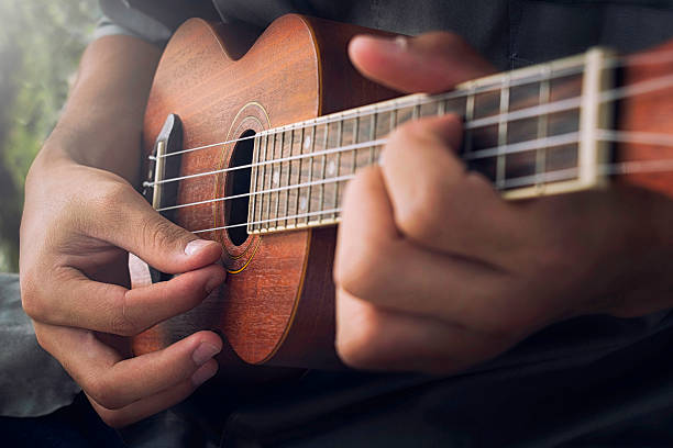 A man playing ukulele in close up view.